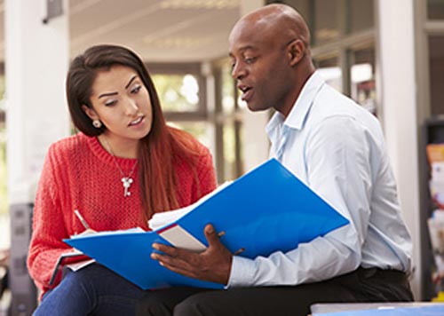 Two people read a document in a binder