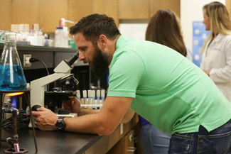 Male student looking through microscope