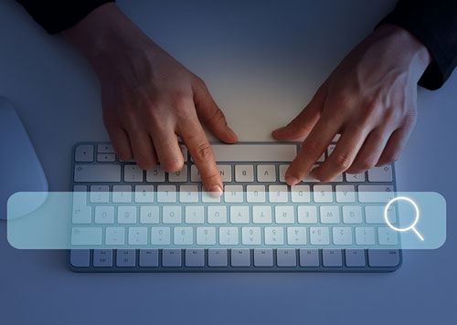 Person typing on a keyboard with a transparent search bar over the keyboard