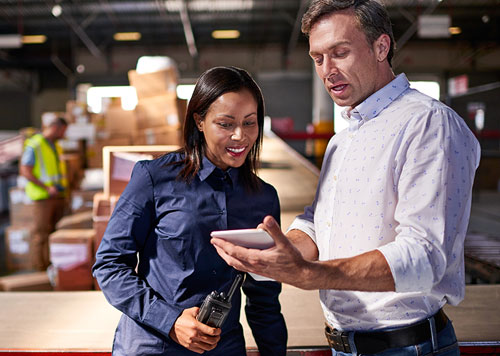 Woman and man standing in a warehouse looking at a tablet