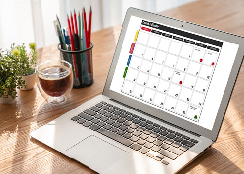 Open laptop sitting on a desk with a monthly calendar showing