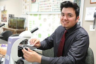 Male student placing specimen under microscope