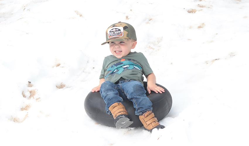 Little boy sliding down the snow hill