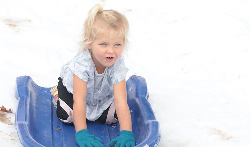 Little girl sliding down the snow hill