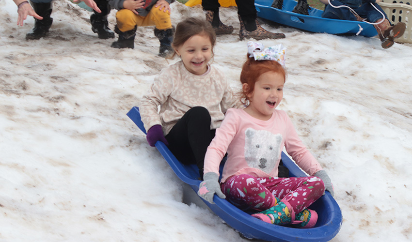 Two girls having fun sliding down the snow hill