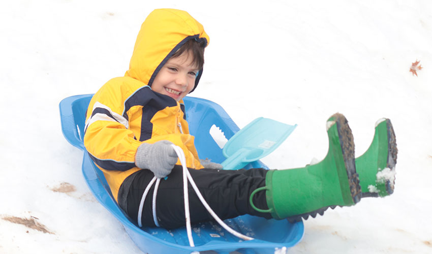 Little boy sliding down the snow hill