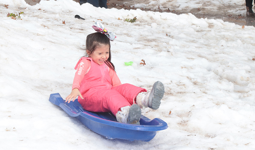 Little girl sliding down the snow hill