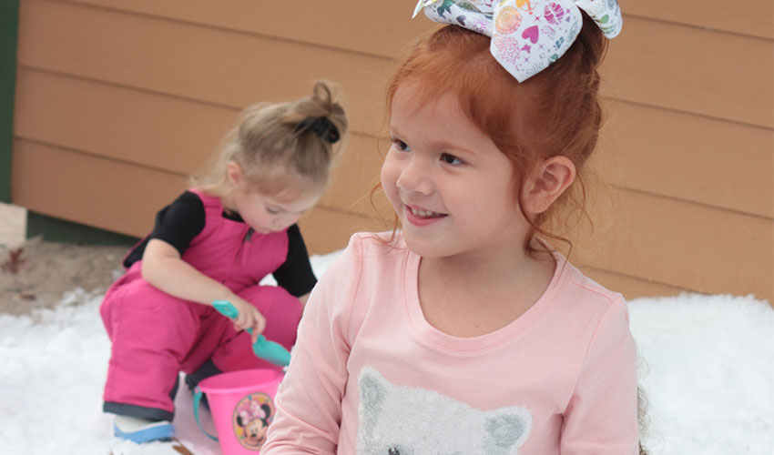 Girl smiling and another girl playing in the back