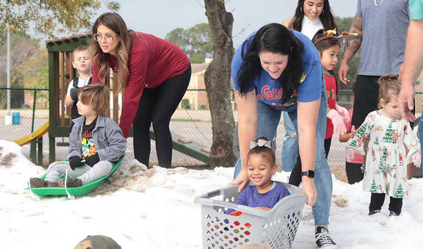 Moms pushing their kids down the snow hill