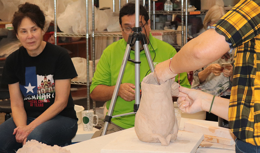 Students observing Mrs. Jeanne making a sculpture.