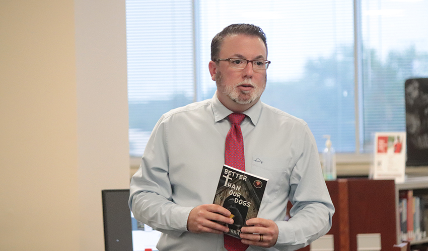 John J. Murray holding his book, "Better than our dogs"