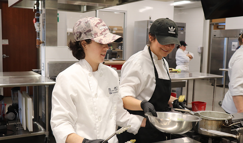Two Culinary Art students having fun while they prepare  some dishes.