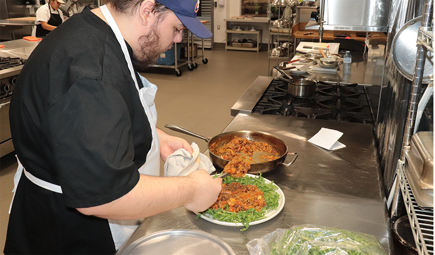 Culinary Arts student spends time plating his culinary dish.