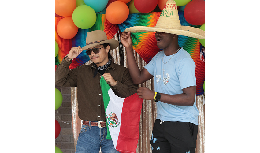 Two students taking a picture with the Mexico flag and their sombreros. 
