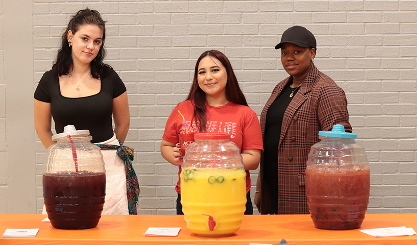 Three individuals providing refreshments at event name.
