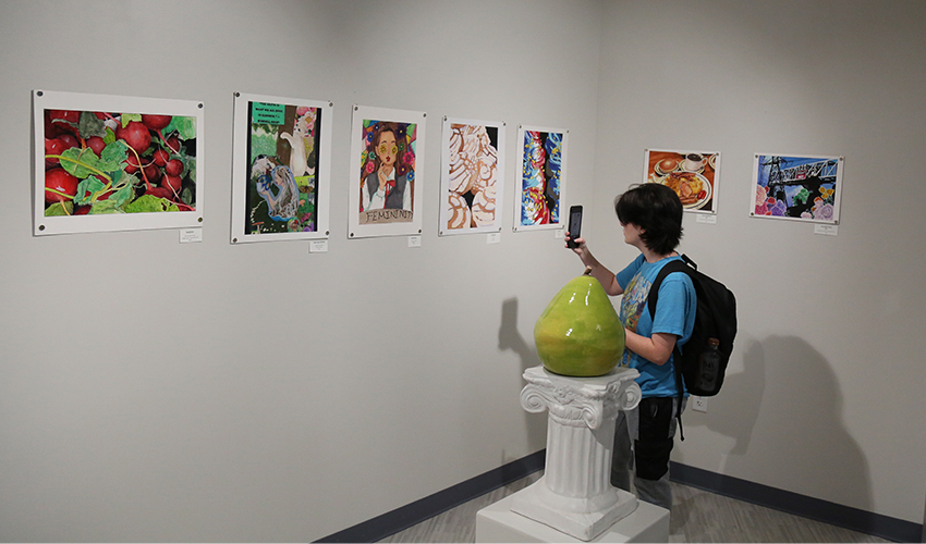 Student taking a picture of the colorful art paintings.