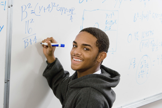 Male student solving math problem on whiteboard